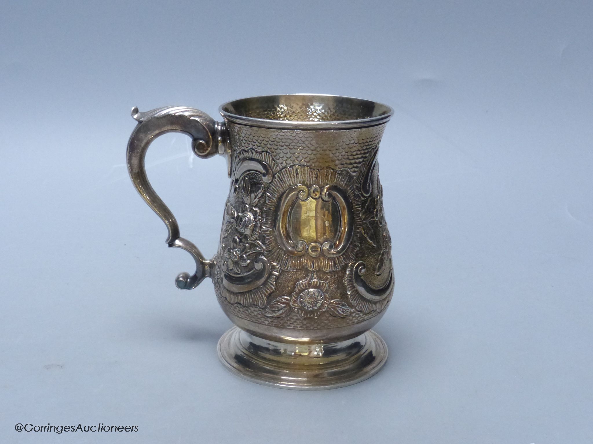 A George III silver baluster mug, with later embossed decoration, London, 1770, 12.7cm, 12.5 oz, indistinct maker's mark.